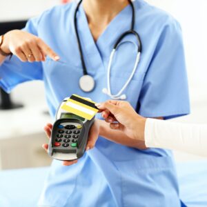 Female doctor standing in her office with payment terminal